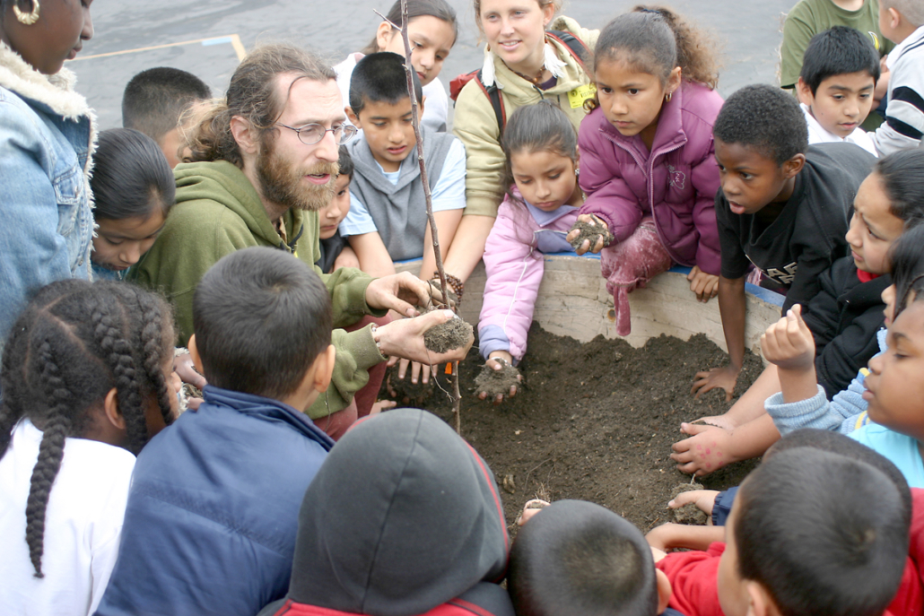 Michael Flynn, cofundador de Common Vision, trabaja con estudiantes que plantan árboles en la Escuela Primaria Grape Street en Los Ángeles.