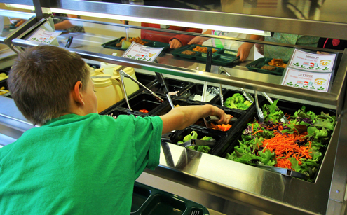 child reaching into salad bar
