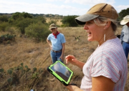 three people in a pasture with a tablet