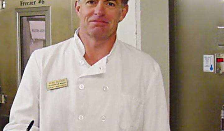 a chef standing next to a freezer door