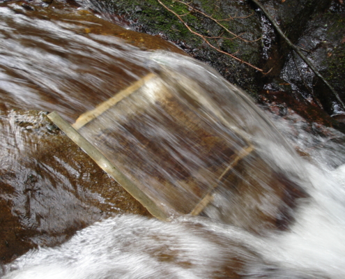 A micro-hydro intake and penstock temporarily divert a portion of the water flow and carry it to the location of the turbine.