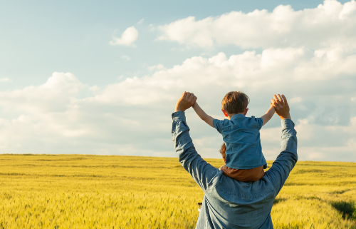 A farmer and his child walk through a wheat field