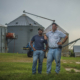 two men standing in front of silos