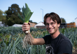 young man holding freshly harvested leek