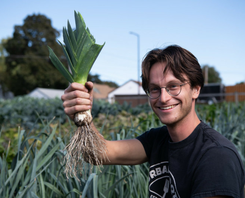 young man holding freshly harvested leek