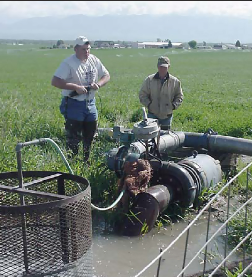 men working on an irrigation pump in a field