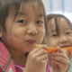 Close-up photo of two children eating fruit