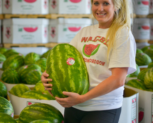 woman holding watermelon in processing warehouse