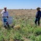 two men stand on pasture land with poster-size map of irrigation