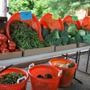 vegetables displayed in orange baskets on and under a table