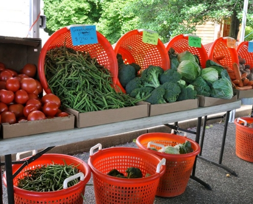 vegetables displayed in orange baskets on and under a table