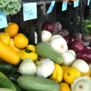 Vegetables (onions and squash) displayed at a farmers market with price signs