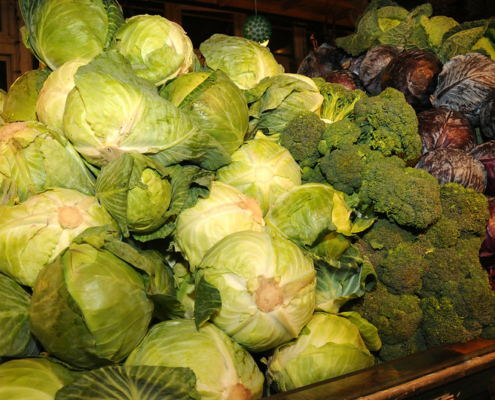 green cabbage, broccoli, and red cabbage piled in a display