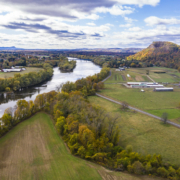 aerial view of farm pastures, forest and river with blue sky with clouds above