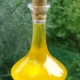 glass bottle of olive oil with a cork stopper, against a green background