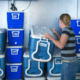 back view of a person facing stacks of blue ice chests inside a cooler