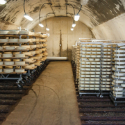 racks of round cheeses in a cheese cave