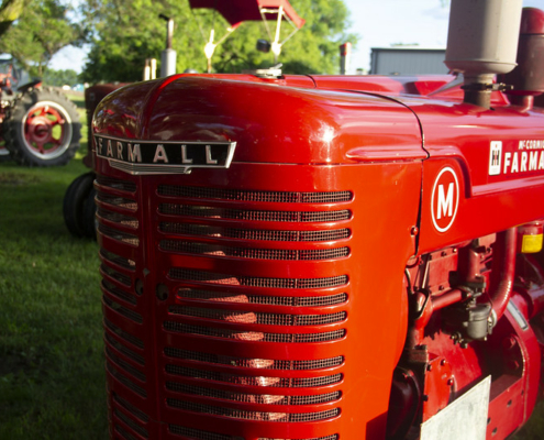 close photo of the front of a historic red Farmall tractor.