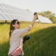 a person standing in a field with solar panels holds up equipment for testing