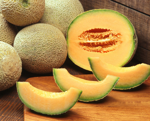 whole cantaloupe, half cantaloupe, and slices on a table