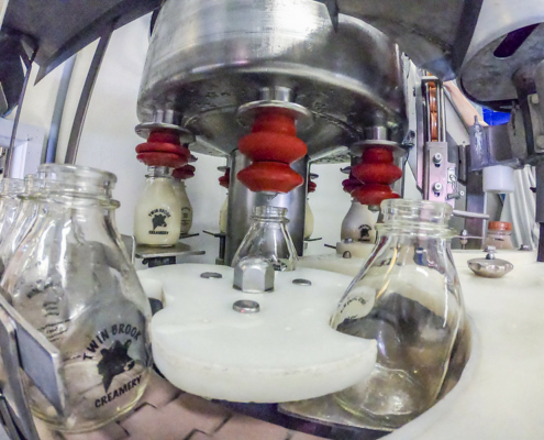 glass milk bottles being filled by equipment