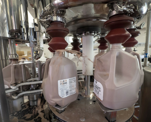 plastic bottles being filled with chocolate milk by a machine