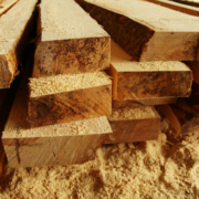 Stacked lumber with sawdust on the ground around it.