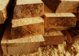 Stacked lumber with sawdust on the ground around it.