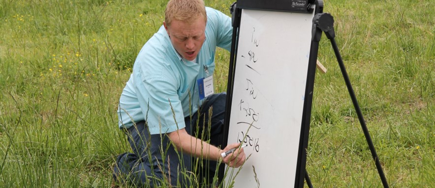 Photo of Jeremy Huff demonstrating grazier's math on a whiteboard