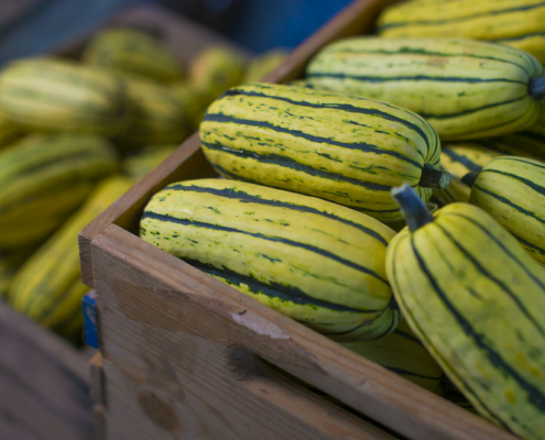 A wooden box holds Delicata squash.