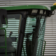 cab of a harvester in front of a metal silo