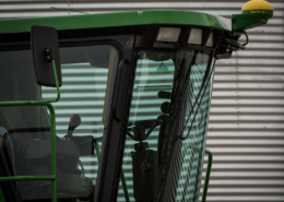 cab of a harvester in front of a metal silo