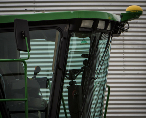 cab of a harvester in front of a metal silo