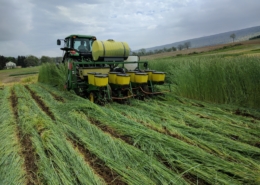 Photo of equipment in the field that is rolling and crimping annual rye and planting soybeans in one pass.