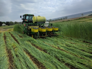 Photo of equipment in the field that is rolling and crimping annual rye and planting soybeans in one pass. 