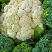 close up of a head of cauliflower surrounded by broccoli