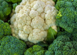 close up of a head of cauliflower surrounded by broccoli