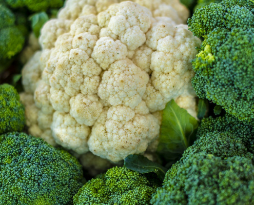 close up of a head of cauliflower surrounded by broccoli