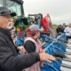 people gathered around a tractor with field equipment as a person explains