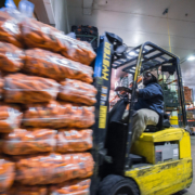 A forklift driver moves bags of carrots through a warehouse.