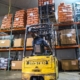 A forklift lifts bagged carrots onto shelves in a warehouse