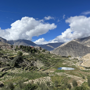 terraced farmland on hills under blue sky with clouds