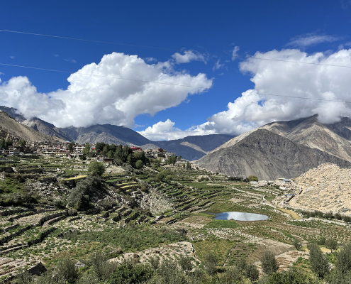 terraced farmland on hills under blue sky with clouds