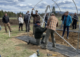 a group of people assembling the frame of a high tunnel