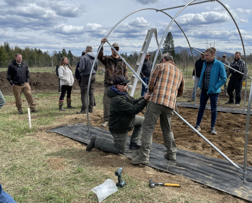 a group of people assembling the frame of a high tunnel