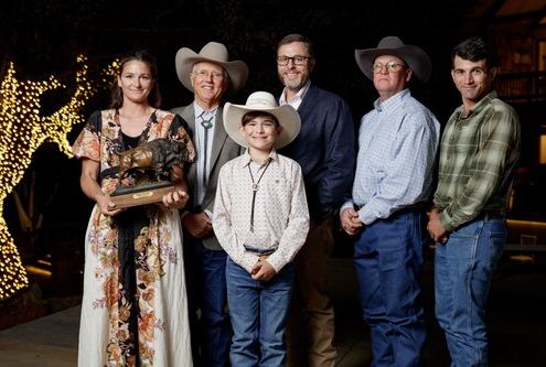group of people indoors posing with bronze statue of buffalo