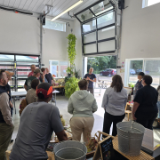 A group stands inside a shop building listening to a presenter