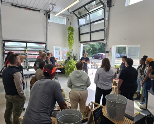 A group stands inside a shop building listening to a presenter