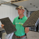 A man holds up empty seedling trays in each hand while speaking.