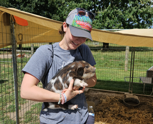 person in hat holding young piglet
